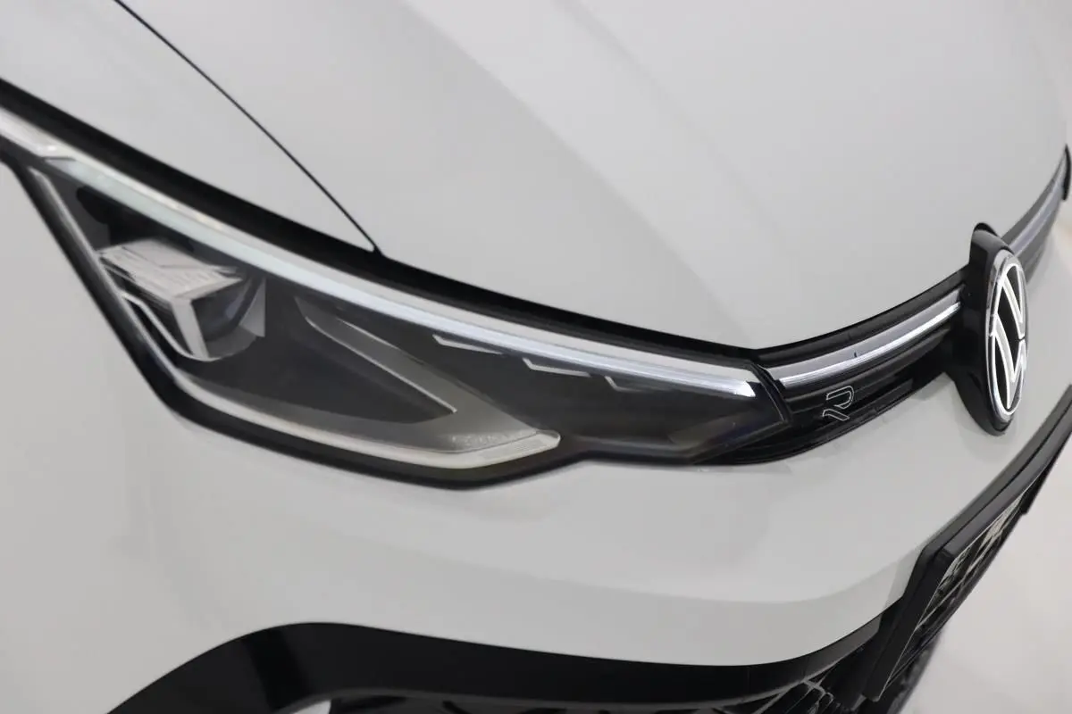 Gros plan sur le phare avant gauche blanc et calandre avec logo Volkswagen et sigle R-LINE.