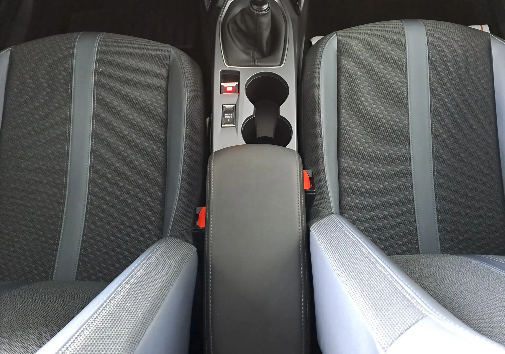 Vue plongeante sur les sièges avant noirs et la console centrale avec levier de vitesse manuelle d'une Peugeot 2008 2020.