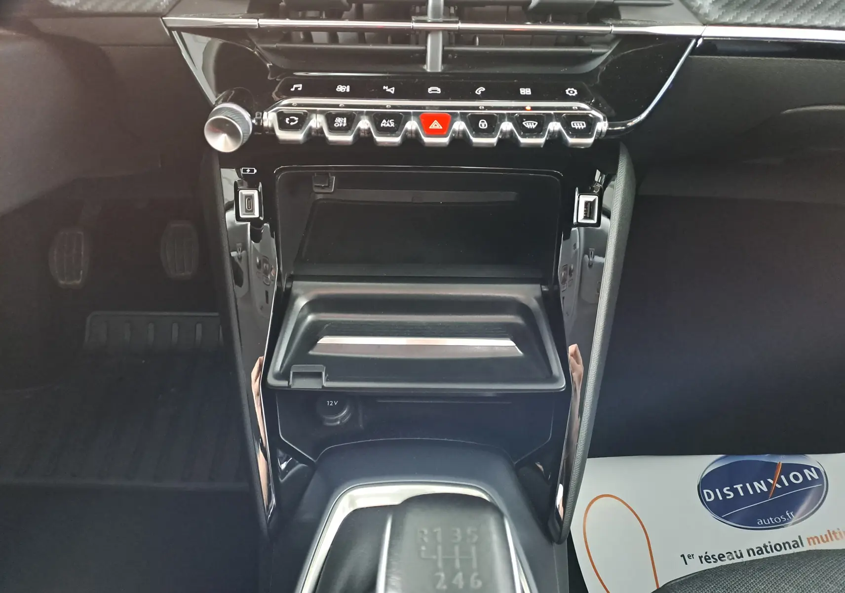 Vue rapprochée de la console centrale noire brillante du Peugeot 2008 bleu Vertigo, avec levier de vitesse manuel et commandes tactiles.