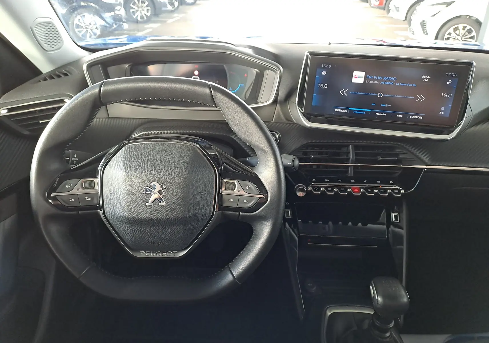 Vue intérieure centrée sur le volant et le tableau de bord numérique du Peugeot 2008 bleu Vertigo, avec écran tactile et commandes intégrées.