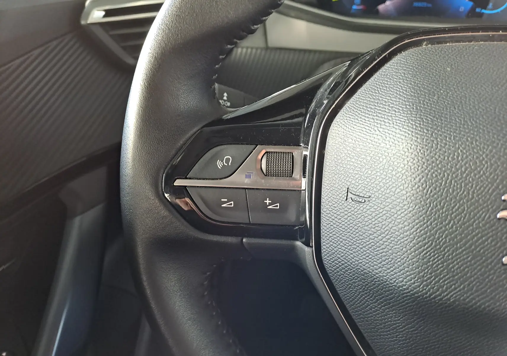 Gros plan sur les commandes gauche du volant en cuir noir du Peugeot 2008 1.2 PureTech 100 Allure 2020.