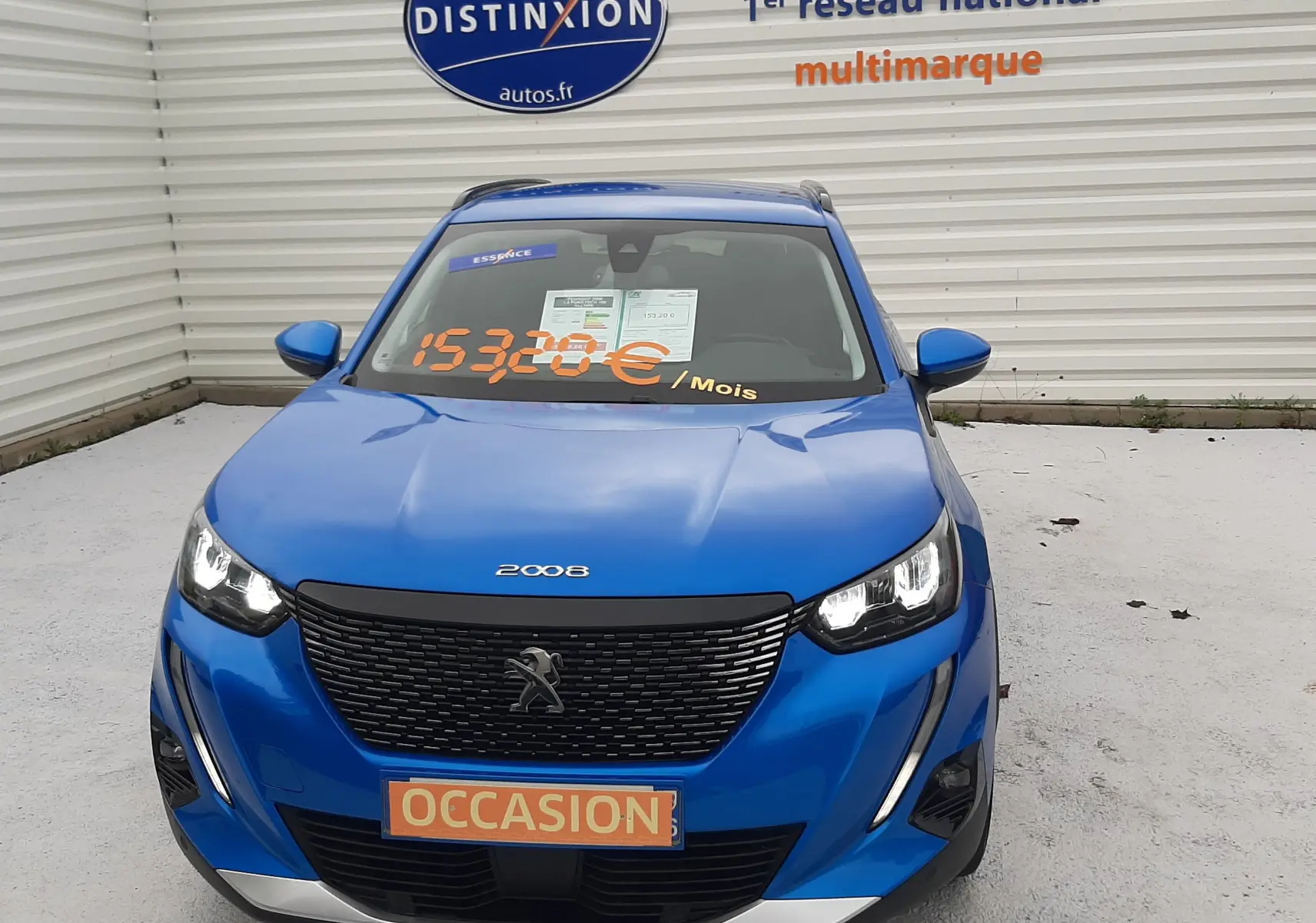 Peugeot 2008 bleu Vertigo vue de face, avec phares allumés et panneau "OCCASION" sur la calandre.