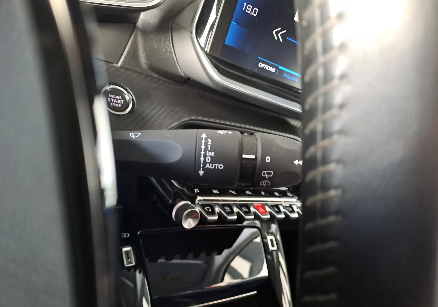 Gros plan sur la commande d'essuie-glace et le bouton start/stop du tableau de bord noir d'un Peugeot 2008 2020.