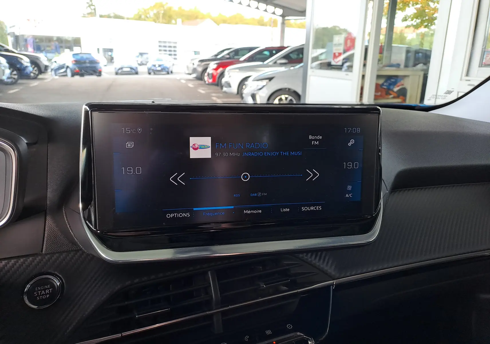 Écran tactile central du tableau de bord du Peugeot 2008 bleu Vertigo, affichant la radio FM dans un intérieur noir.