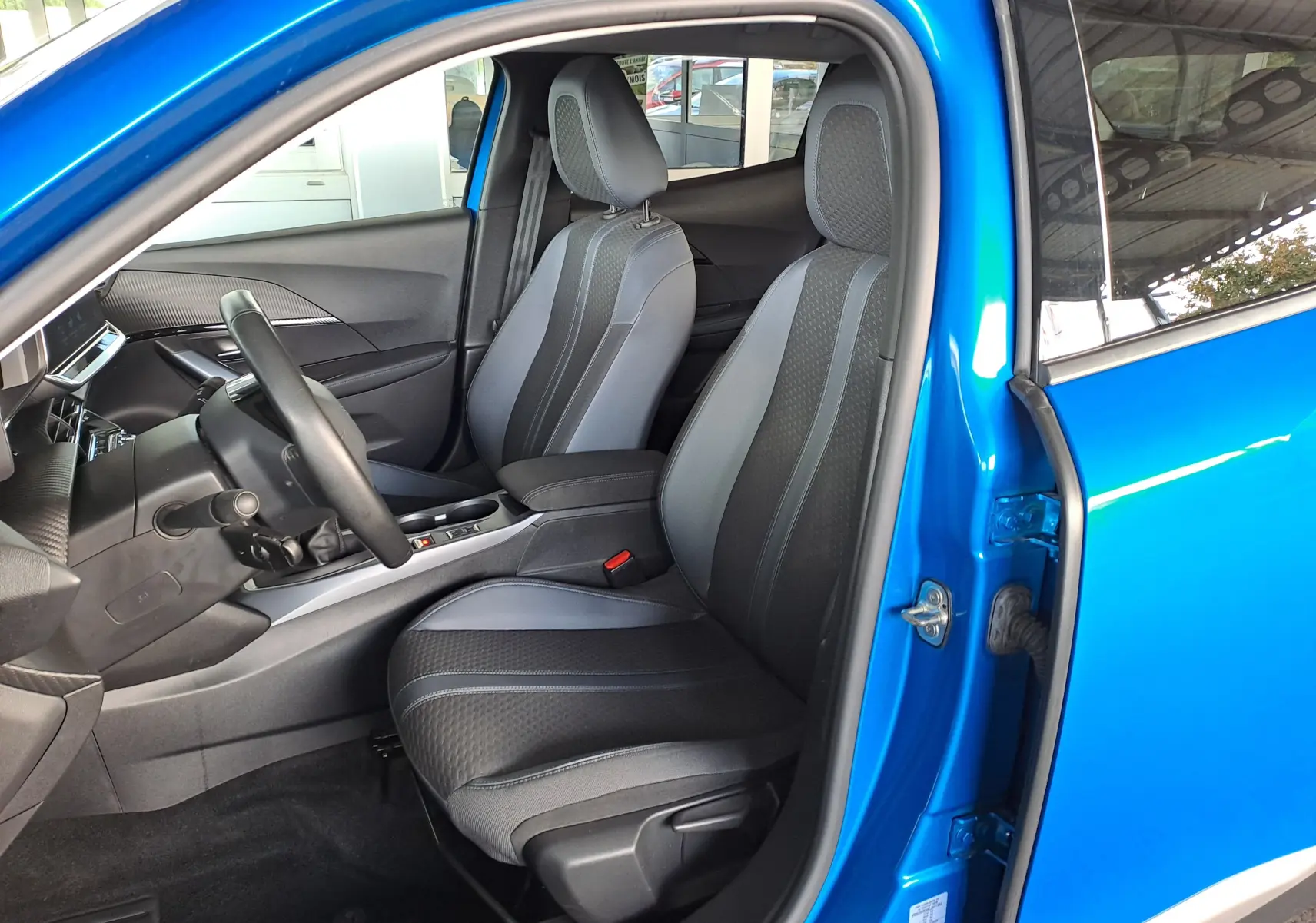 Vue intérieure côté conducteur du Peugeot 2008 bleu Vertigo 2020, sièges tissu noir et gris avec volant et console centrale visibles.