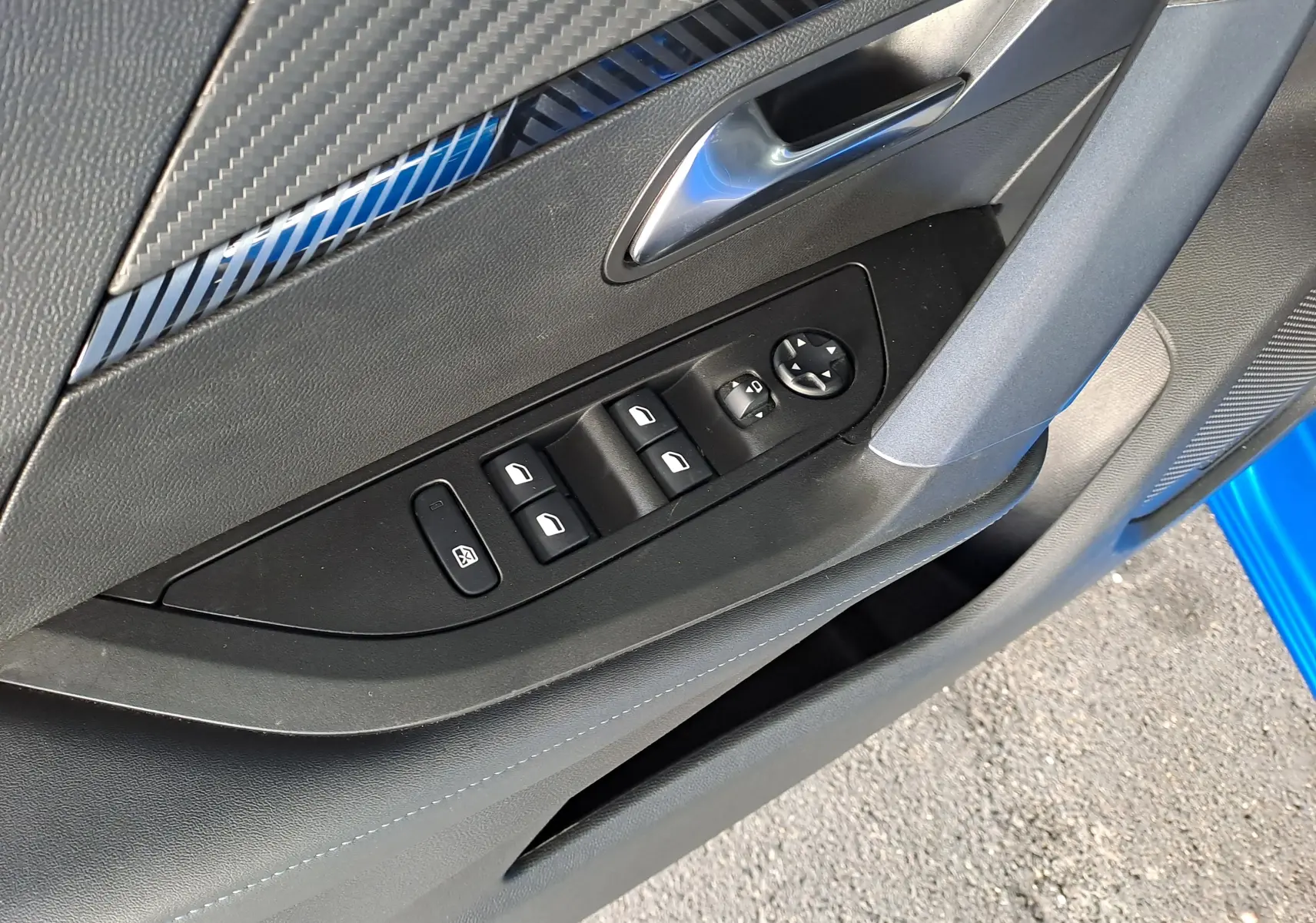 Détail de la porte côté conducteur du Peugeot 2008 bleu Vertigo, montrant les commandes des vitres et rétroviseurs.