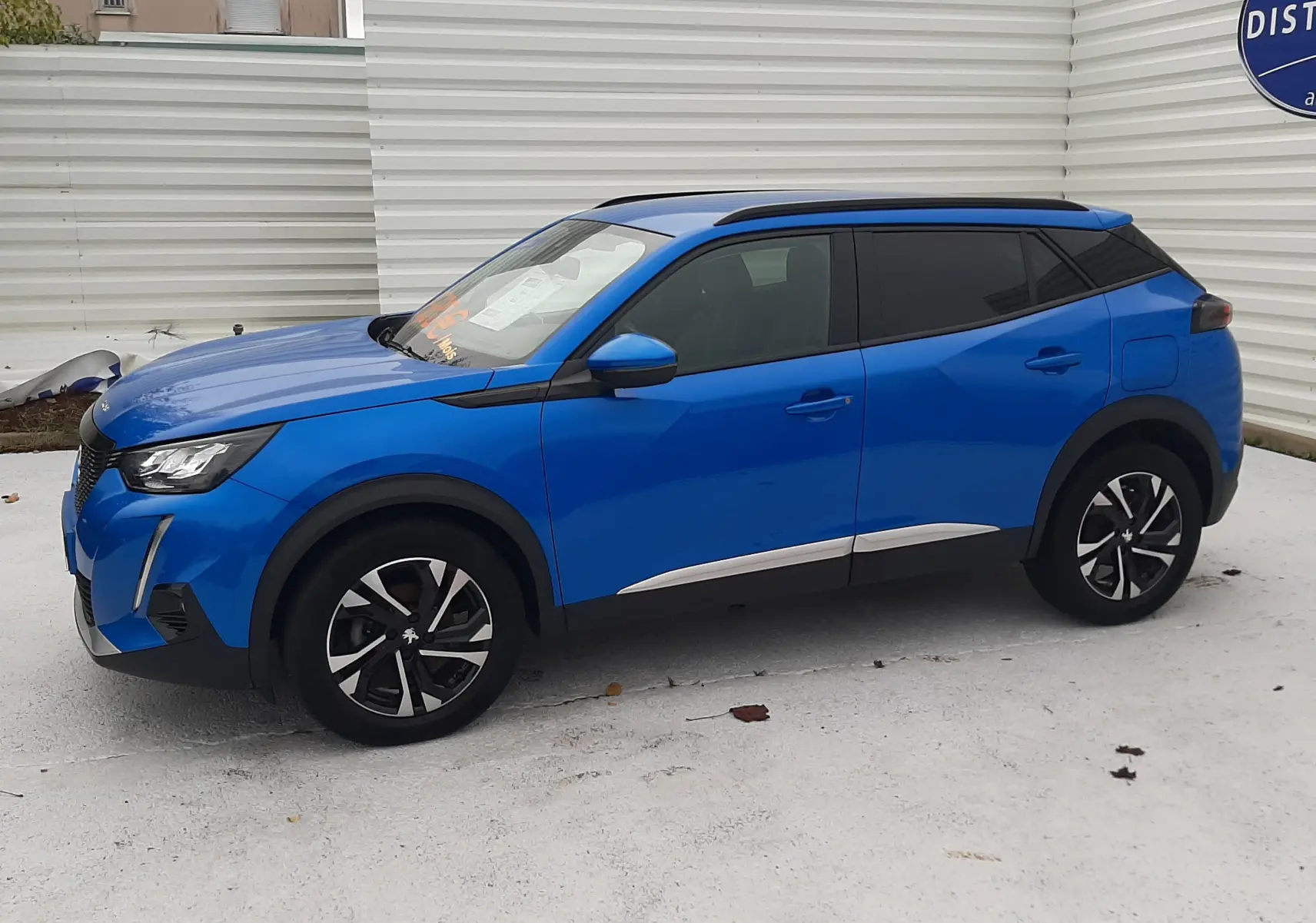 Peugeot 2008 1.2 PureTech 100 Allure bleu Vertigo vu de profil côté gauche, jantes alliage noires et toit noir.
