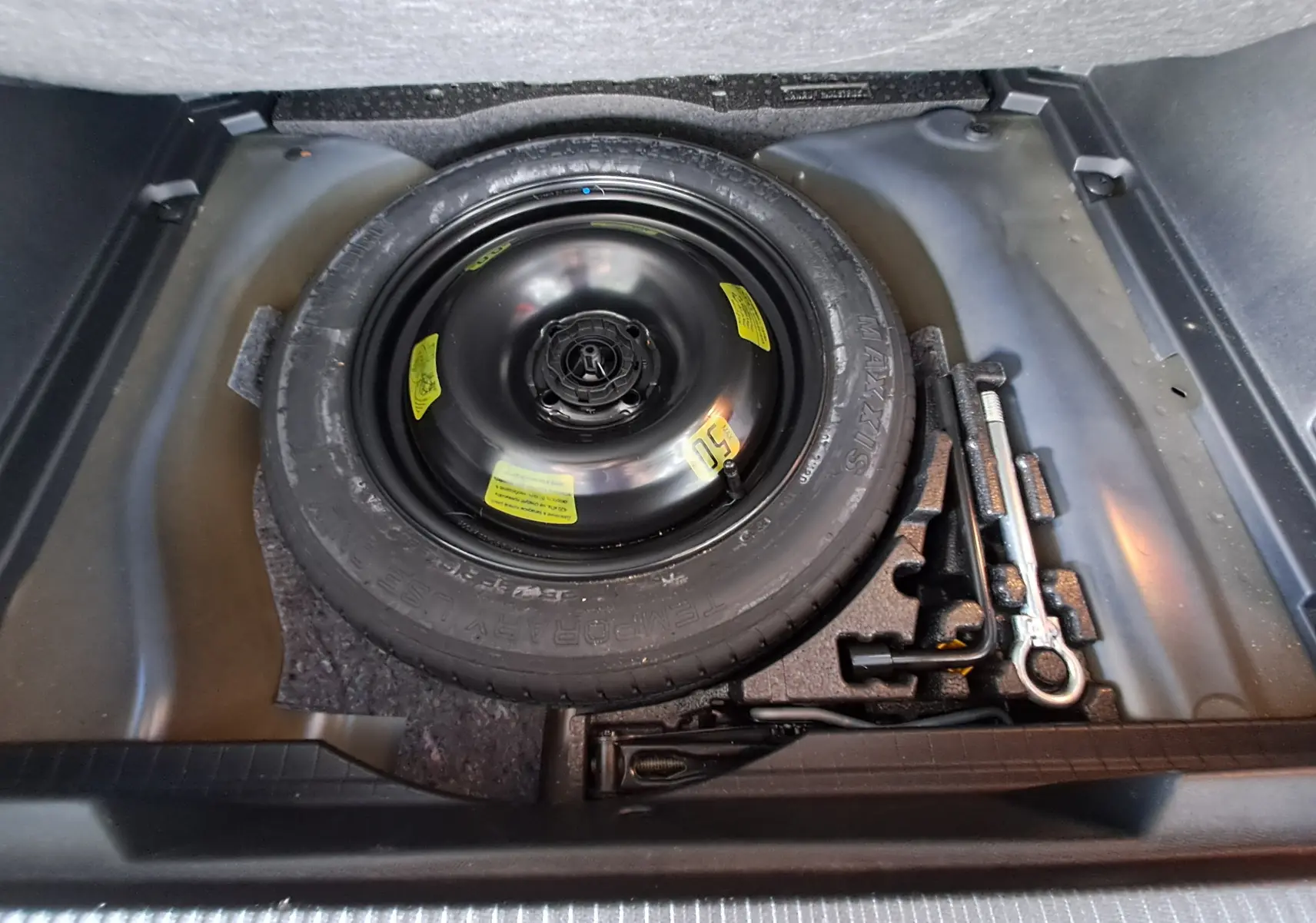 Vue plongeante sur la roue de secours et les outils de bord dans le coffre d'une Peugeot 2008 bleu Vertigo 2020
