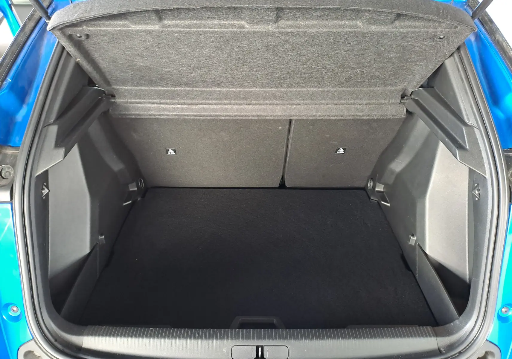 Coffre ouvert vu de l'arrière d'un Peugeot 2008 bleu Vertigo, montrant un espace de chargement propre et spacieux.