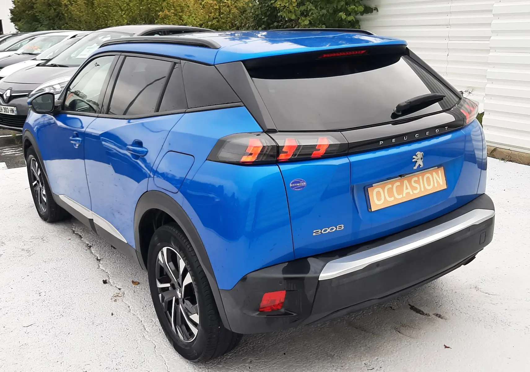 Vue 3/4 arrière droite d'un Peugeot 2008 bleu Vertigo avec feux arrière LED et toit noir brillant.