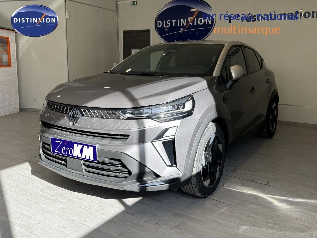 Renault Captur 1.6 E-Tech Full Hybrid 145ch en gris cassiopée métal, vue 3/4 avant droit en intérieur showroom.