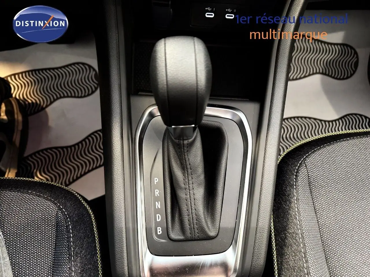 Le levier de vitesses automatique du Renault Captur 2025 en gros plan, entouré de sièges en tissu gris.