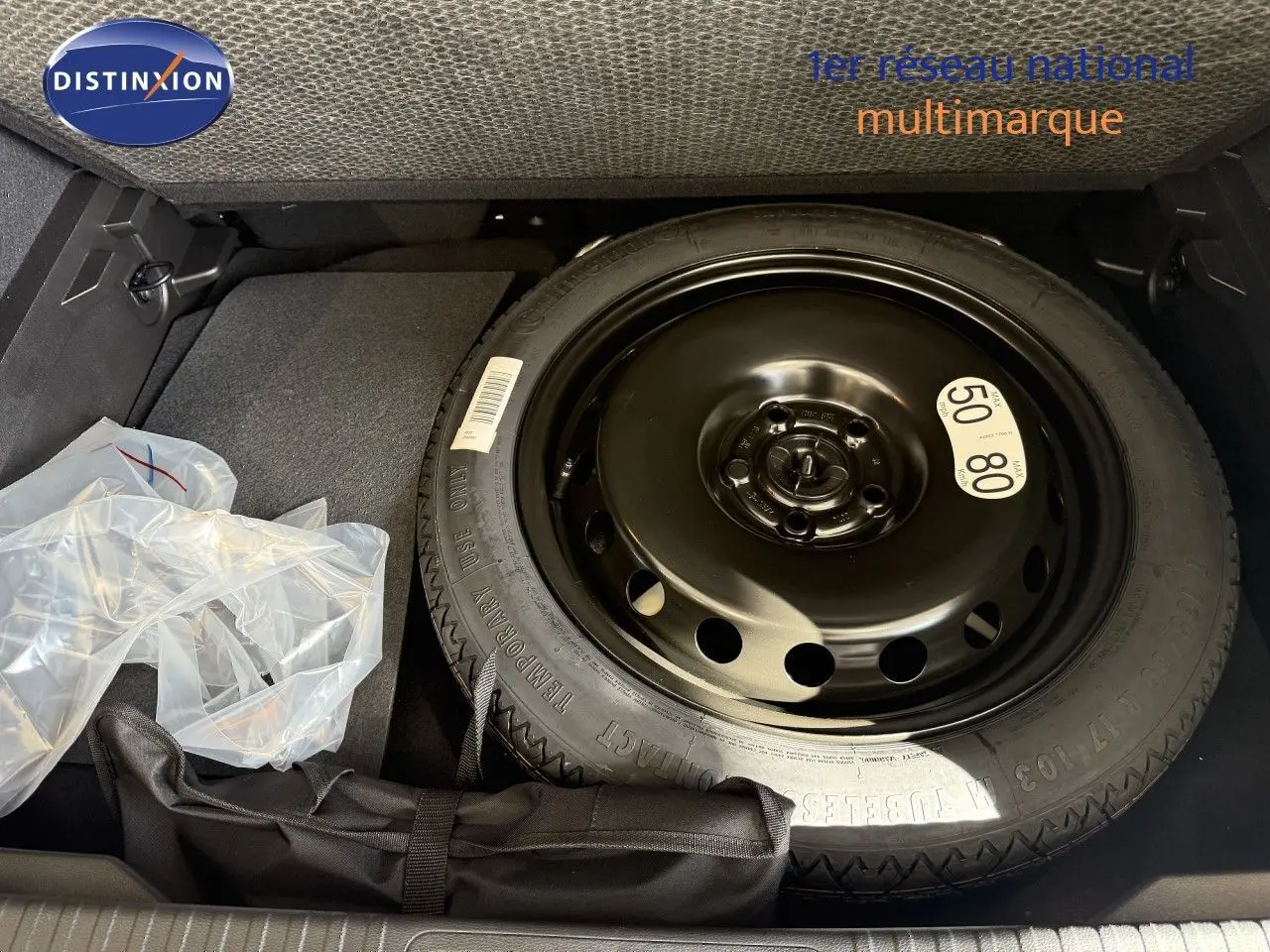 Vue du coffre avec roue de secours noire et accessoires de bord dans un Renault Captur gris Cassiopée métal toit gris.