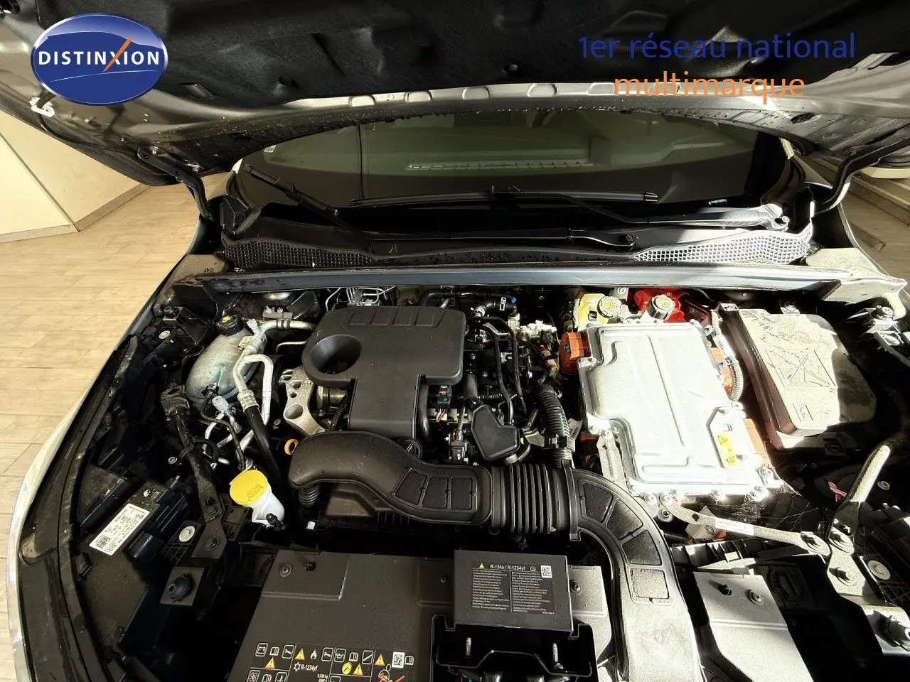 Vue rapprochée du moteur hybride sous capot ouvert du Renault Captur gris Cassiopée, montrant les composants techniques.