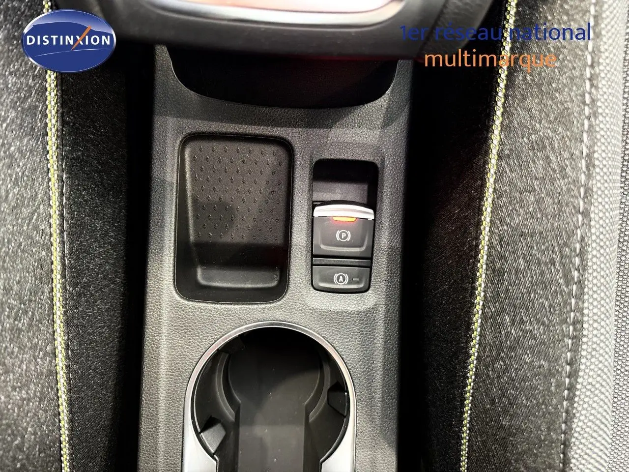 Gros plan sur la console centrale du Renault Captur 2025, montrant porte-gobelet et commandes électroniques, avec surpiqûres jaunes.