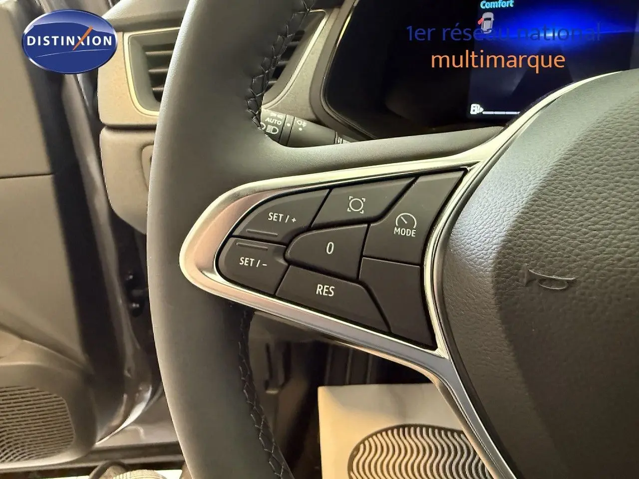 Gros plan sur les commandes au volant du Renault Captur 2025, version hybride, avec finition cuir gris et affichage digital en arrière-plan.