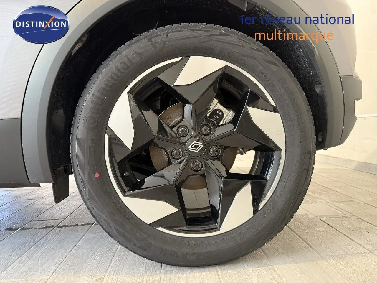 Gros plan sur la roue avant droite du Renault Captur gris Cassiopée, jante alliage noire et argentée à design géométrique.