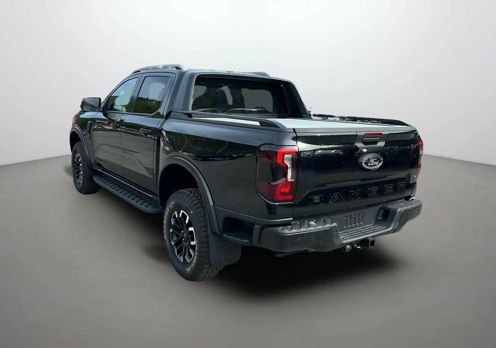 Ford Ranger 2025 noir agate, vue 3/4 arrière droit, avec arceau sport et rideau coulissant sur la benne.