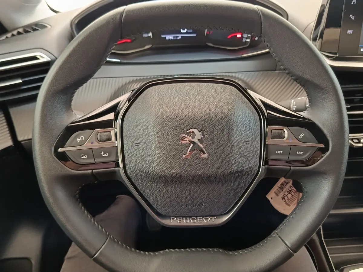 Vue rapprochée du volant cuir noir de la Peugeot 208 PureTech 75 S&S Style 2023 avec commandes intégrées.