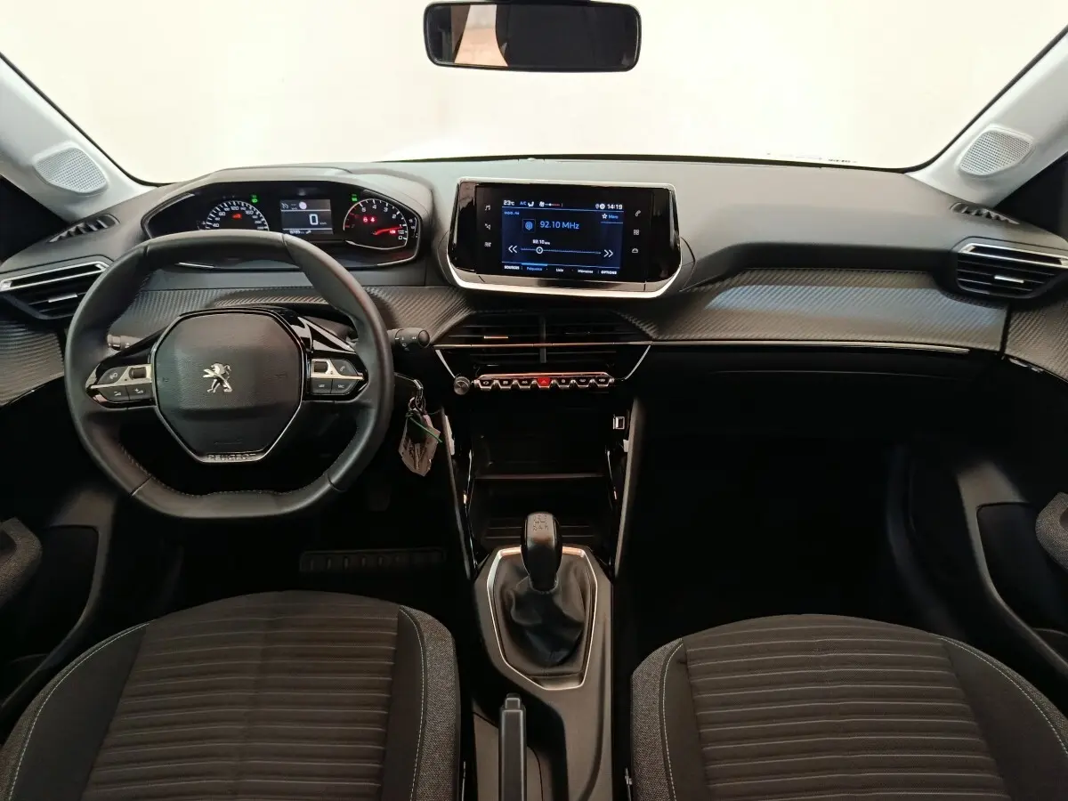 Vue intérieure frontale du tableau de bord et volant cuir noir de la Peugeot 208 PureTech 75 S&S Style 2023.