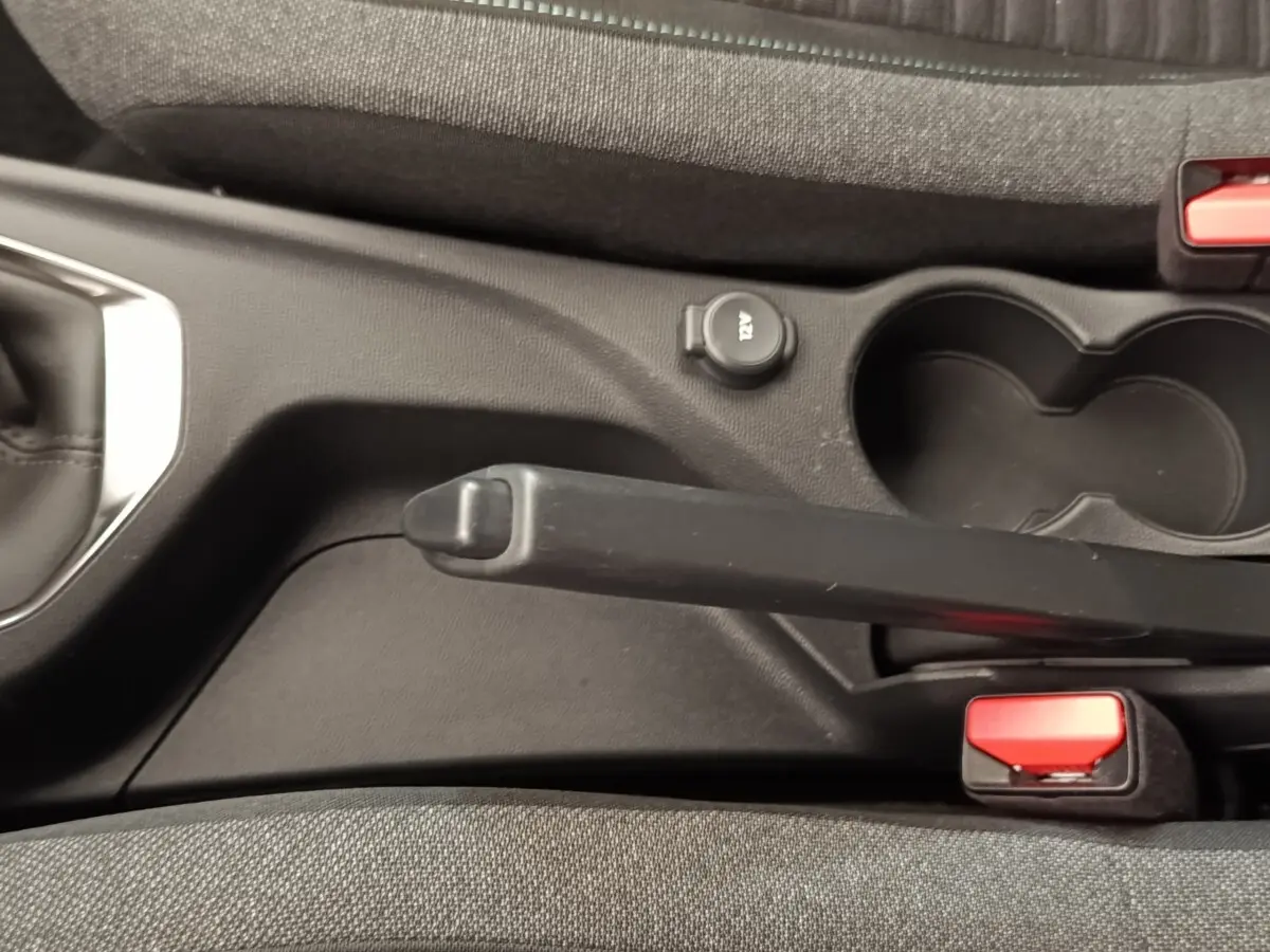 Vue rapprochée de la console centrale noire et tissu gris avec frein à main et prise 12V de la Peugeot 208 2023.