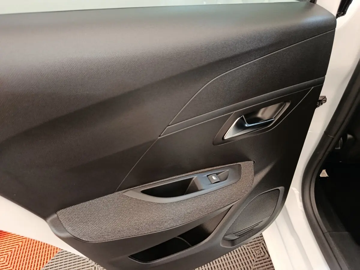 Vue intérieure de la porte avant droite noire et grise de la Peugeot 208 PureTech 75 S&S Style 2023, avec bouton de lève-vitre.