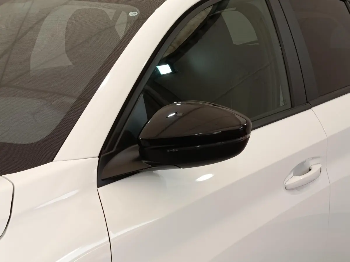 Gros plan sur le rétroviseur noir et la portière blanche côté conducteur d'une Peugeot 208 2023 PureTech Style.