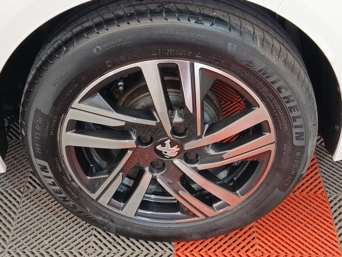 Gros plan sur la roue avant droite d'une Peugeot 208 2023 avec jante alliage noire et argentée, pneu Michelin.