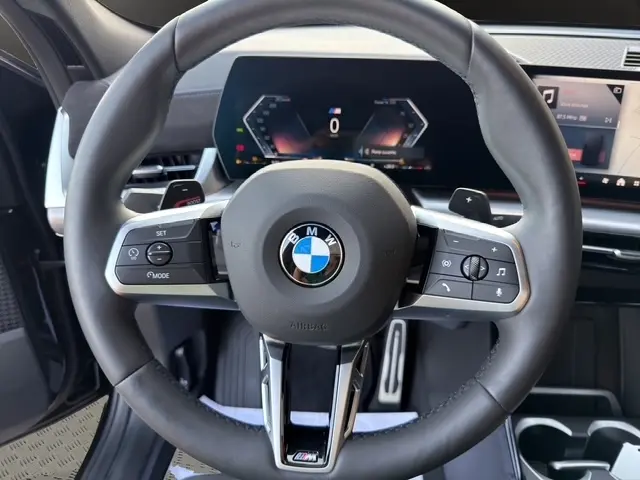 Vue rapprochée du volant cuir et alu multifonctions noir du BMW X2 sDrive20d M Sport 2025 avec tableau de bord digital.