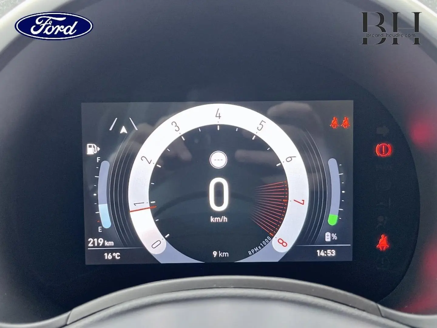 Tableau de bord numérique de Ford, affichant la vitesse à 0 km/h et divers indicateurs, cadran central circulaire.