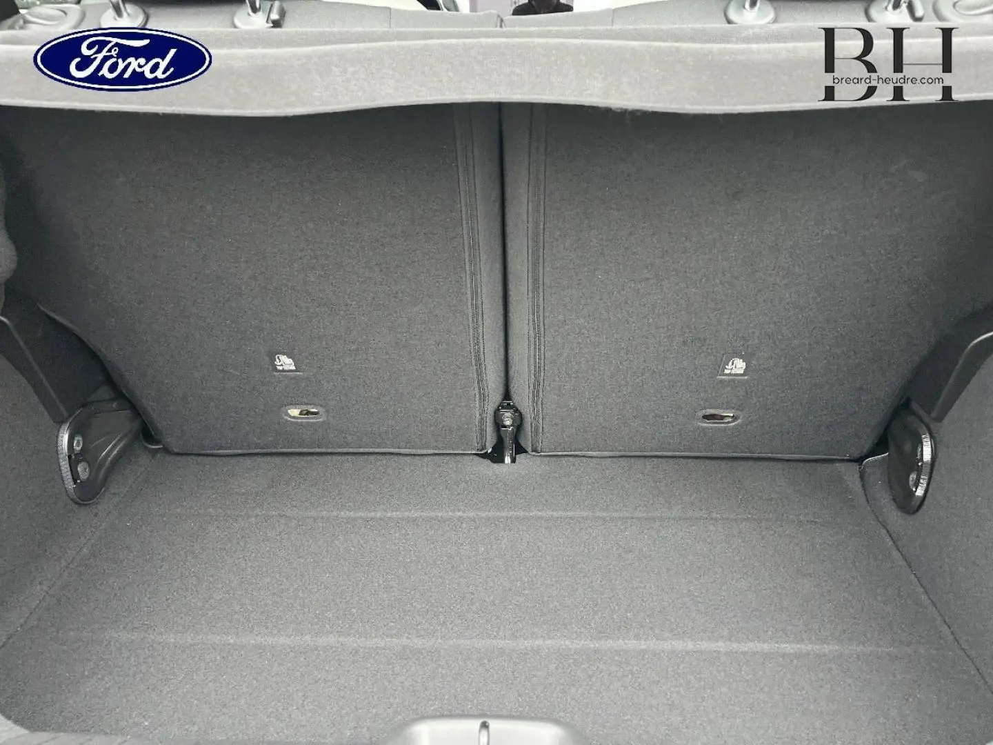 Coffre ouvert d'une FIAT 500 Ice White pastel, montrant la banquette arrière rabattable et le tapis de coffre gris.