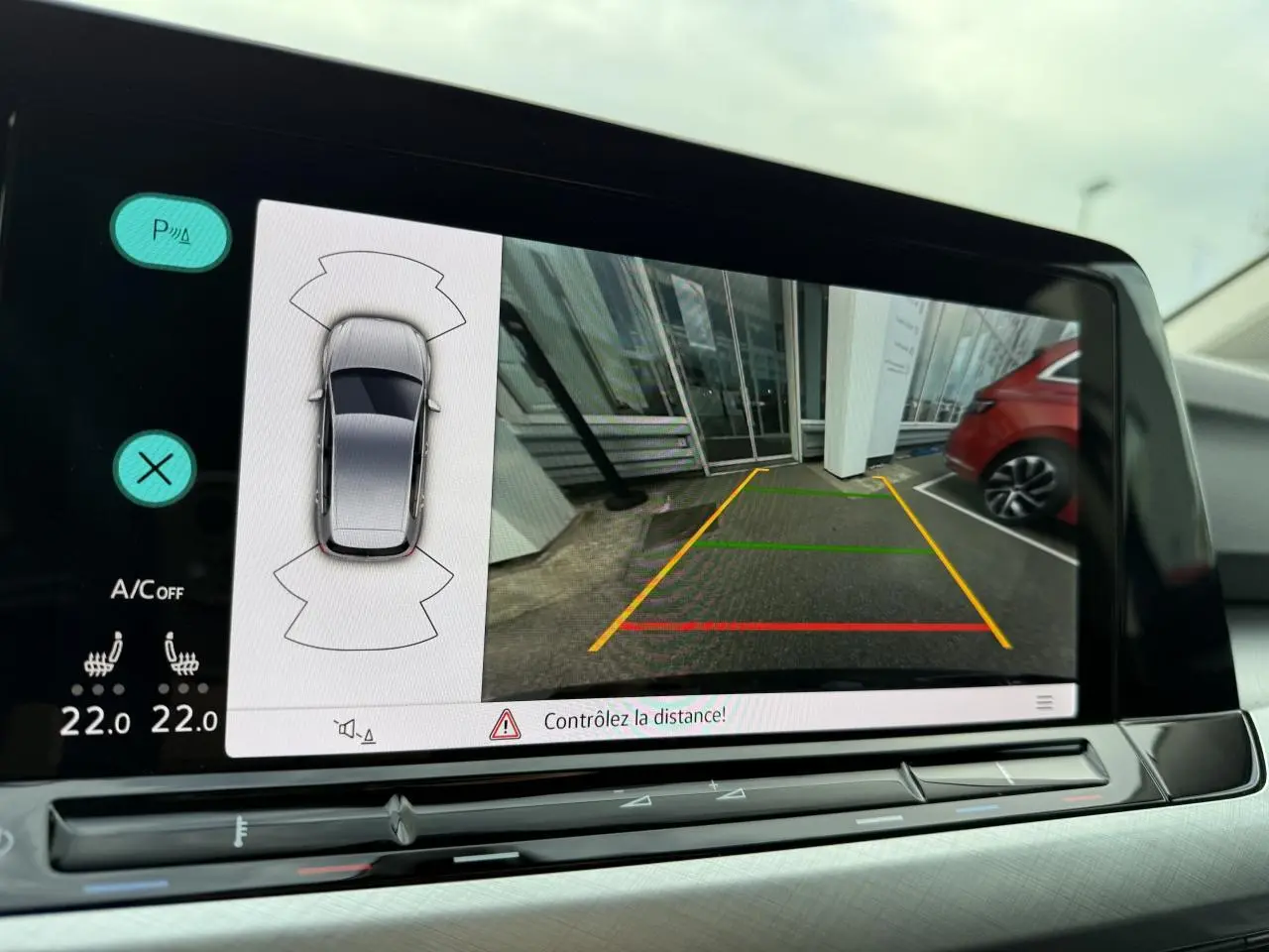 Écran de caméra de recul affichant l’aide au stationnement du Volkswagen Golf bleu Atlantique métallisé, vue intérieure.