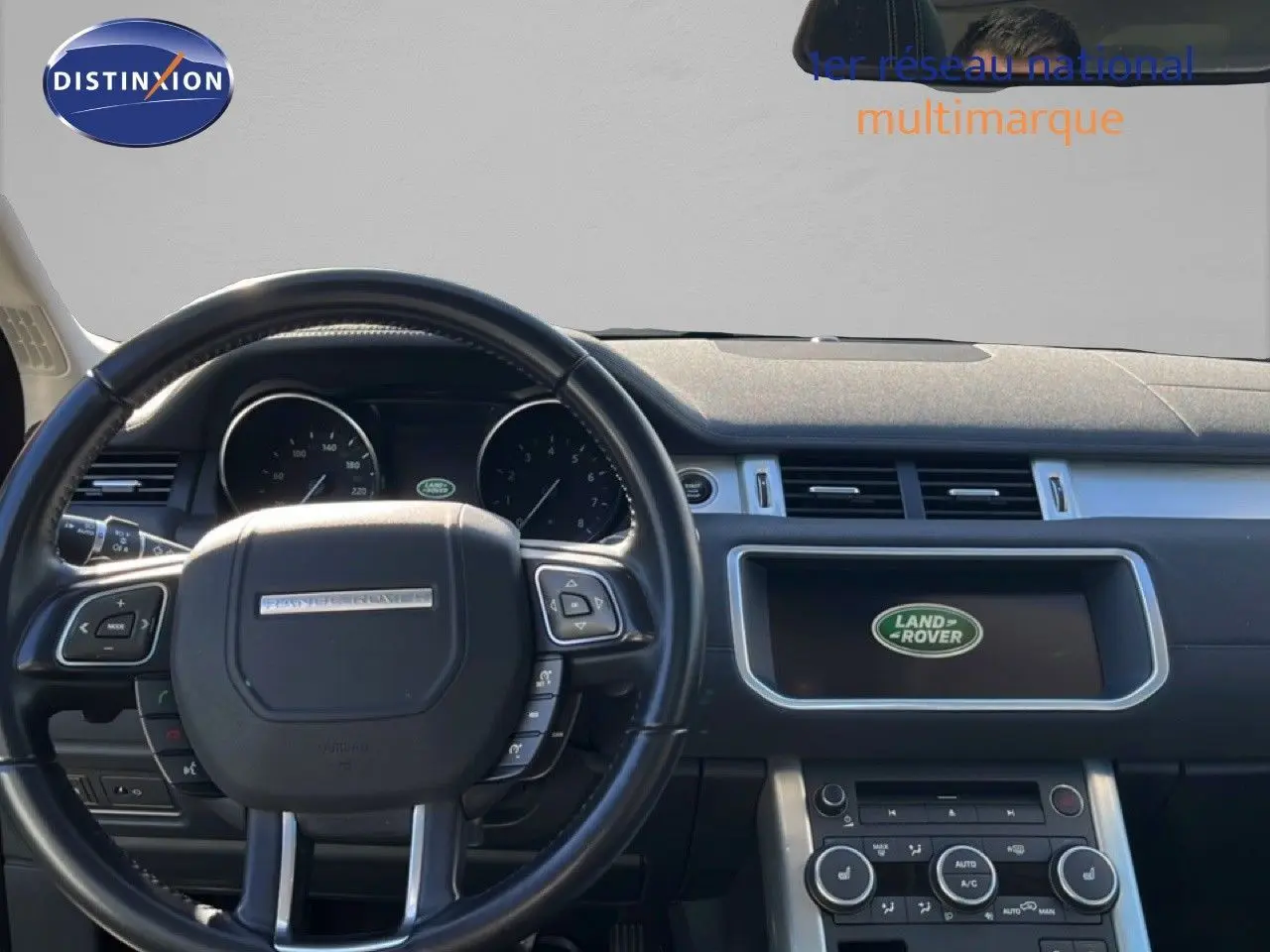 Vue intérieure centrée sur le volant noir et le tableau de bord du Range Rover Evoque 2017 avec écran Land Rover allumé.