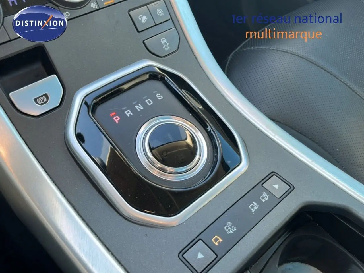 Gros plan sur la molette de sélection de la boîte automatique dans l'habitacle noir du Range Rover Evoque blanc.