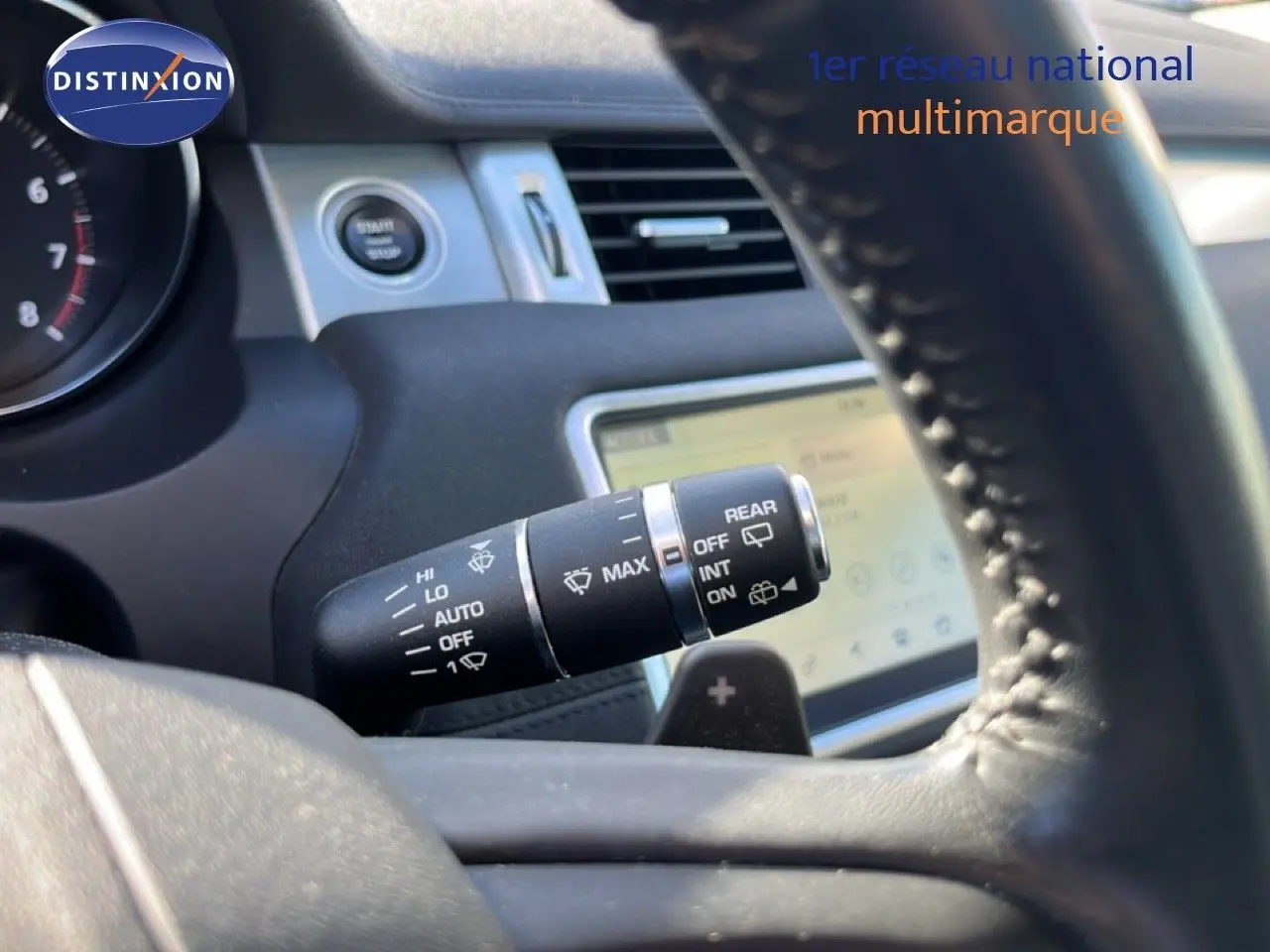 Gros plan sur la commande des essuie-glaces à l'intérieur d'un Range Rover Evoque blanc, avec volant en cuir noir visible.