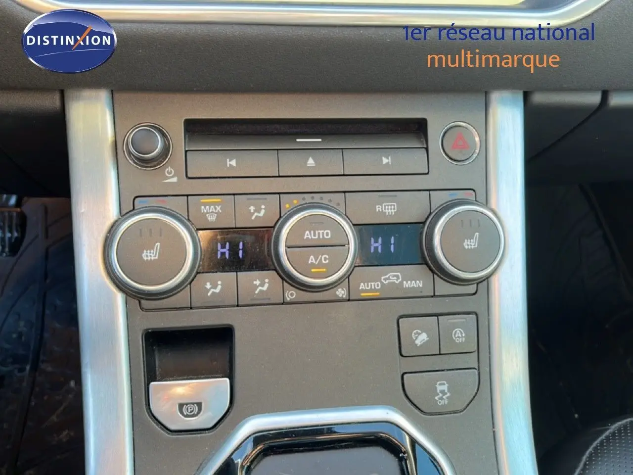 Console centrale du Range Rover Evoque blanc 2017, vue rapprochée des commandes de climatisation et du frein à main électrique.