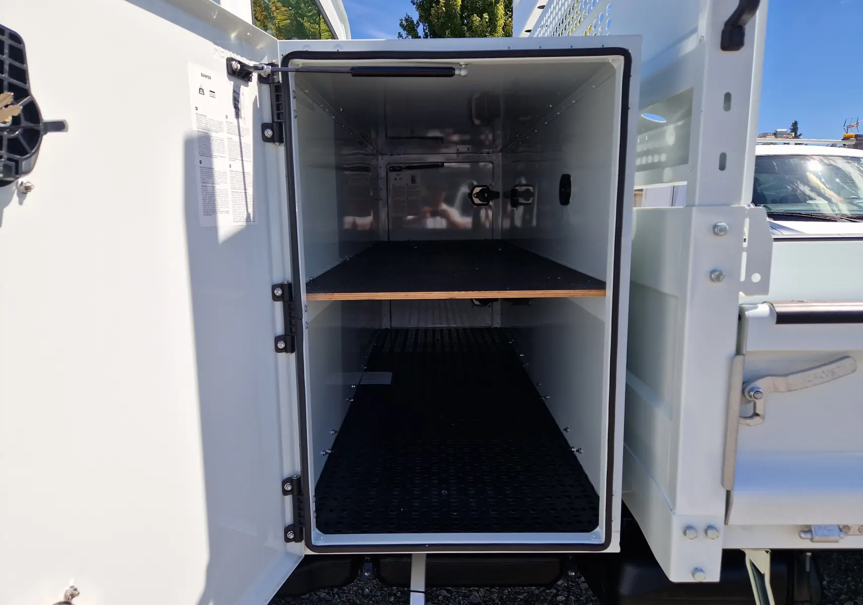 Vue rapprochée du coffre blanc ouvert du Daily Chassis Cabine Iveco 35C16 avec étagère intérieure visible.