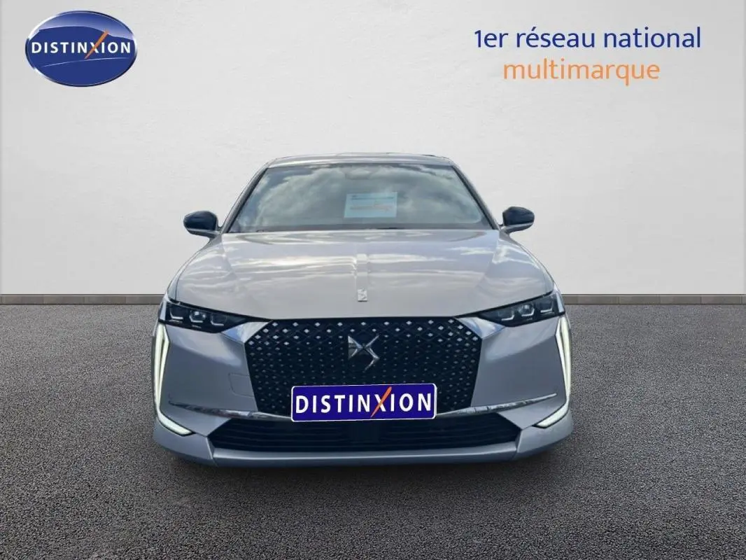 Vue frontale d'une DS4 2024 gris clair avec calandre noire à motifs et feux diurnes verticaux LED distinctifs.