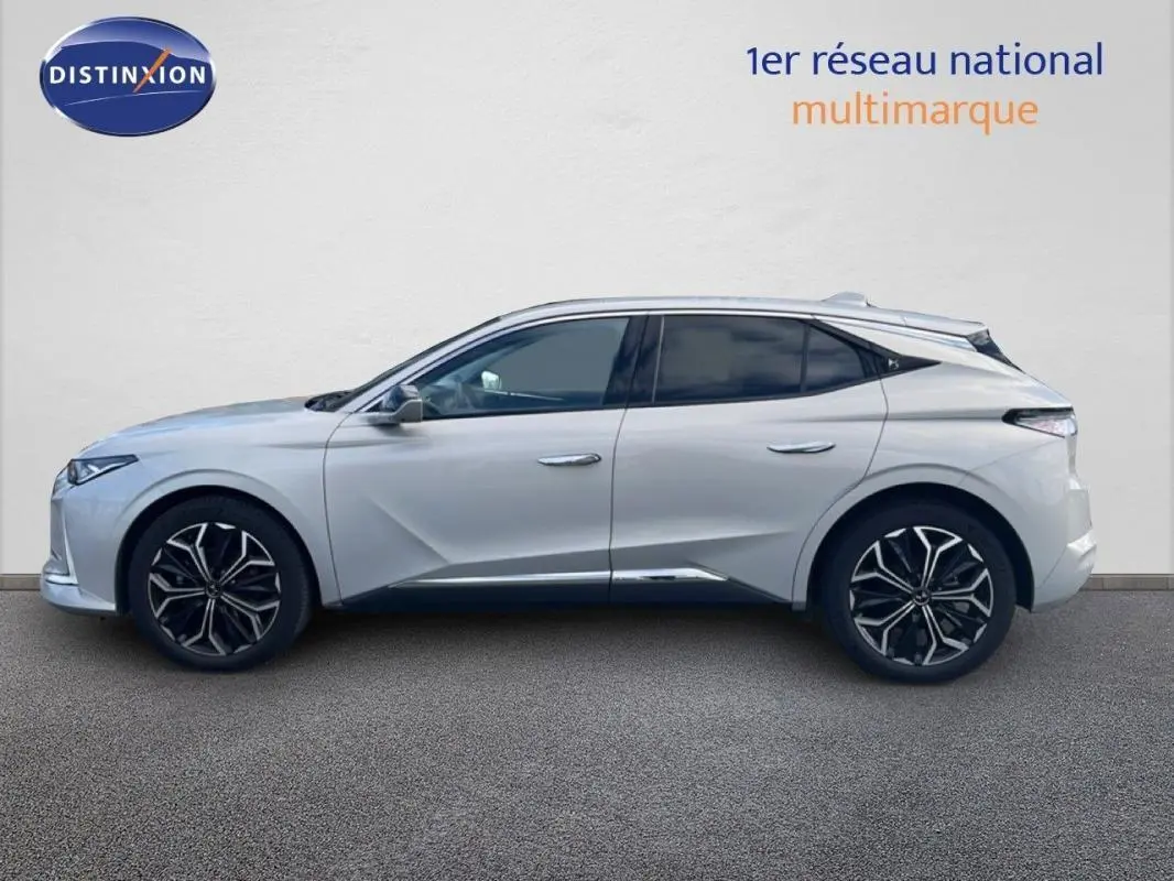 Vue de profil côté gauche d'une DS4 2024 blanche avec jantes noires et détails chromés sous un mur clair.