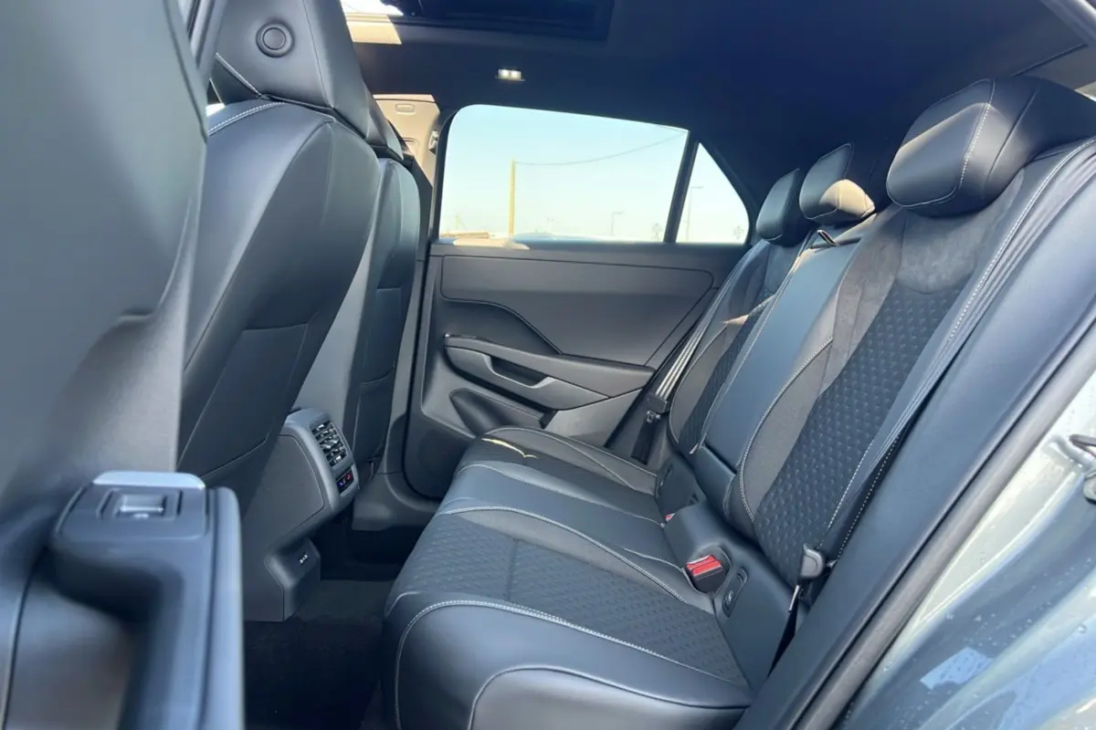 Vue intérieure arrière droite du Volkswagen T-Roc 2026 gris loup, montrant la banquette en tissu et cuir avec surpiqûres contrastées.