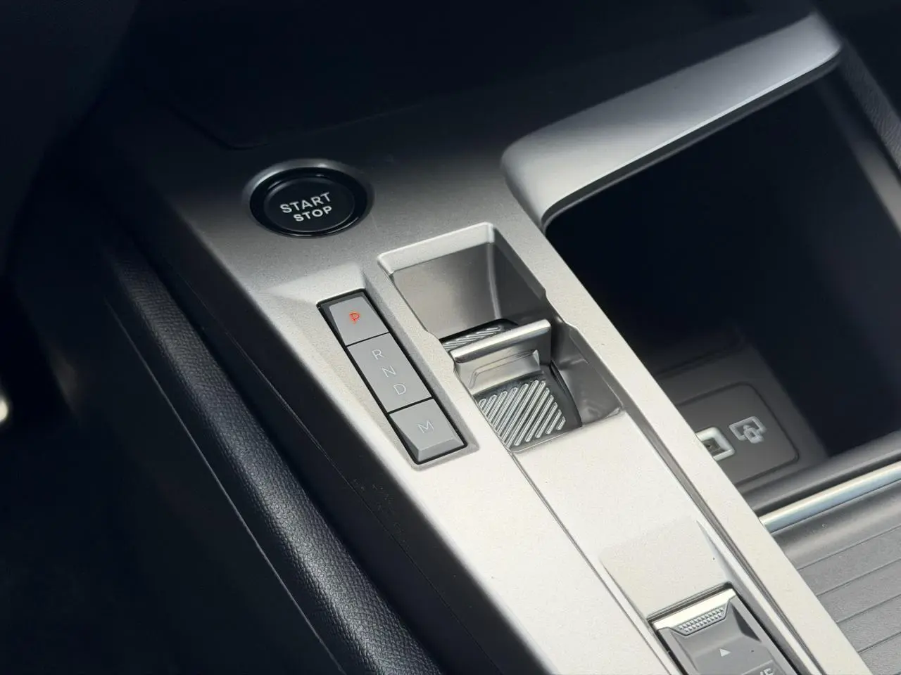 Gros plan sur la console centrale argentée avec bouton Start/Stop et levier de vitesse automatique de la Peugeot 308 Hybrid.