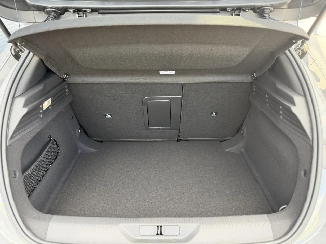 Coffre ouvert de la Peugeot 308 NV Hybrid 145 GT e-DSC6 gris Selenium, montrant un espace de chargement propre et bien fini.