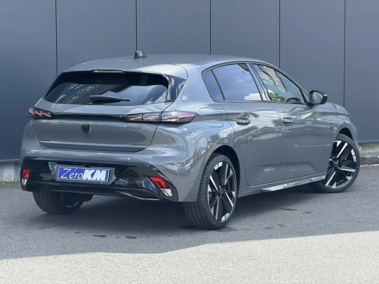 Peugeot 308 NV Hybrid gris Selenium vue 3/4 arrière droit, jantes alliage bi-tons et feux arrière LED 3 griffes.