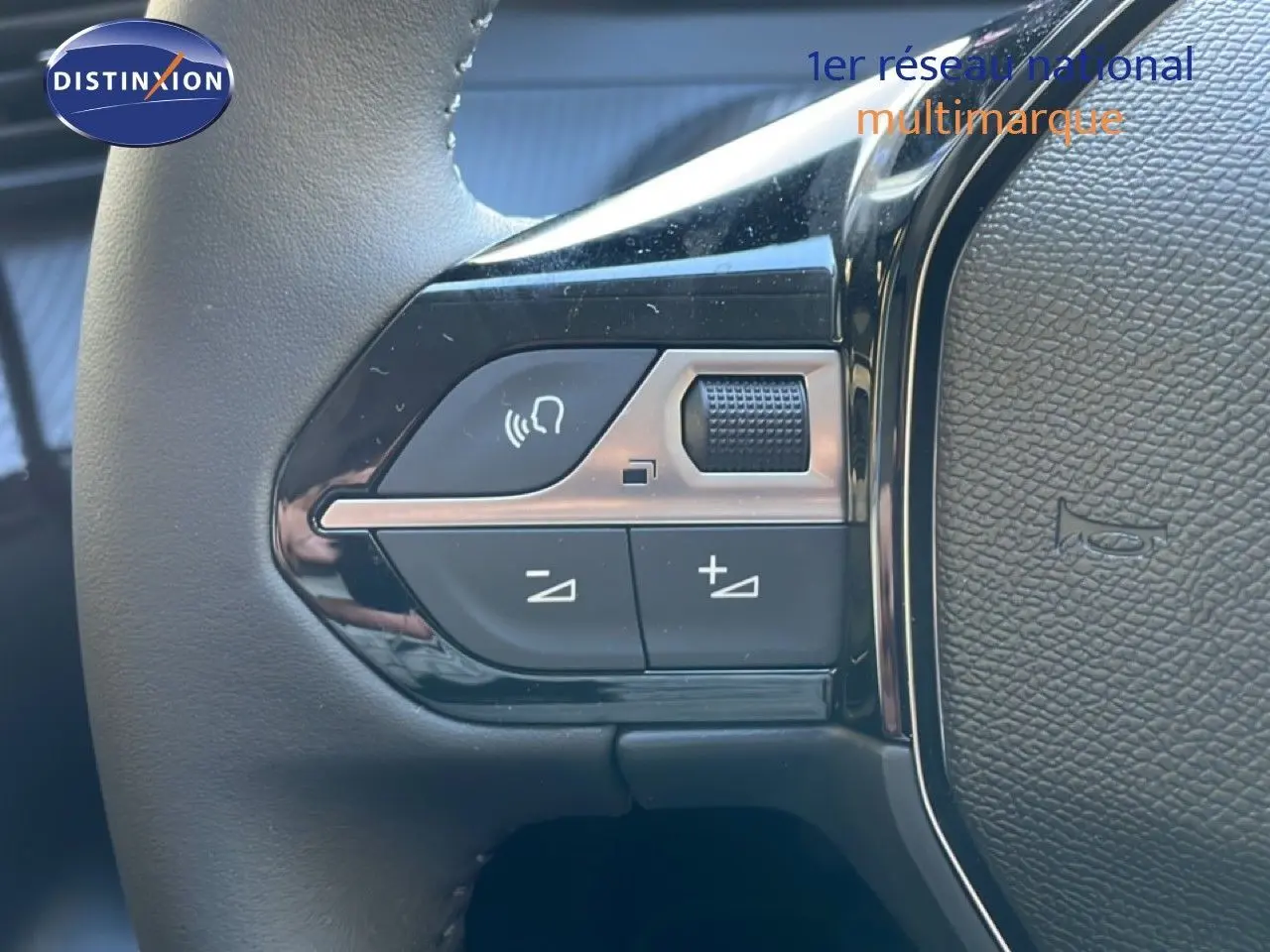 Gros plan sur les commandes de volume et de téléphone au volant noir de la Peugeot 208 Hybrid 110ch Allure.