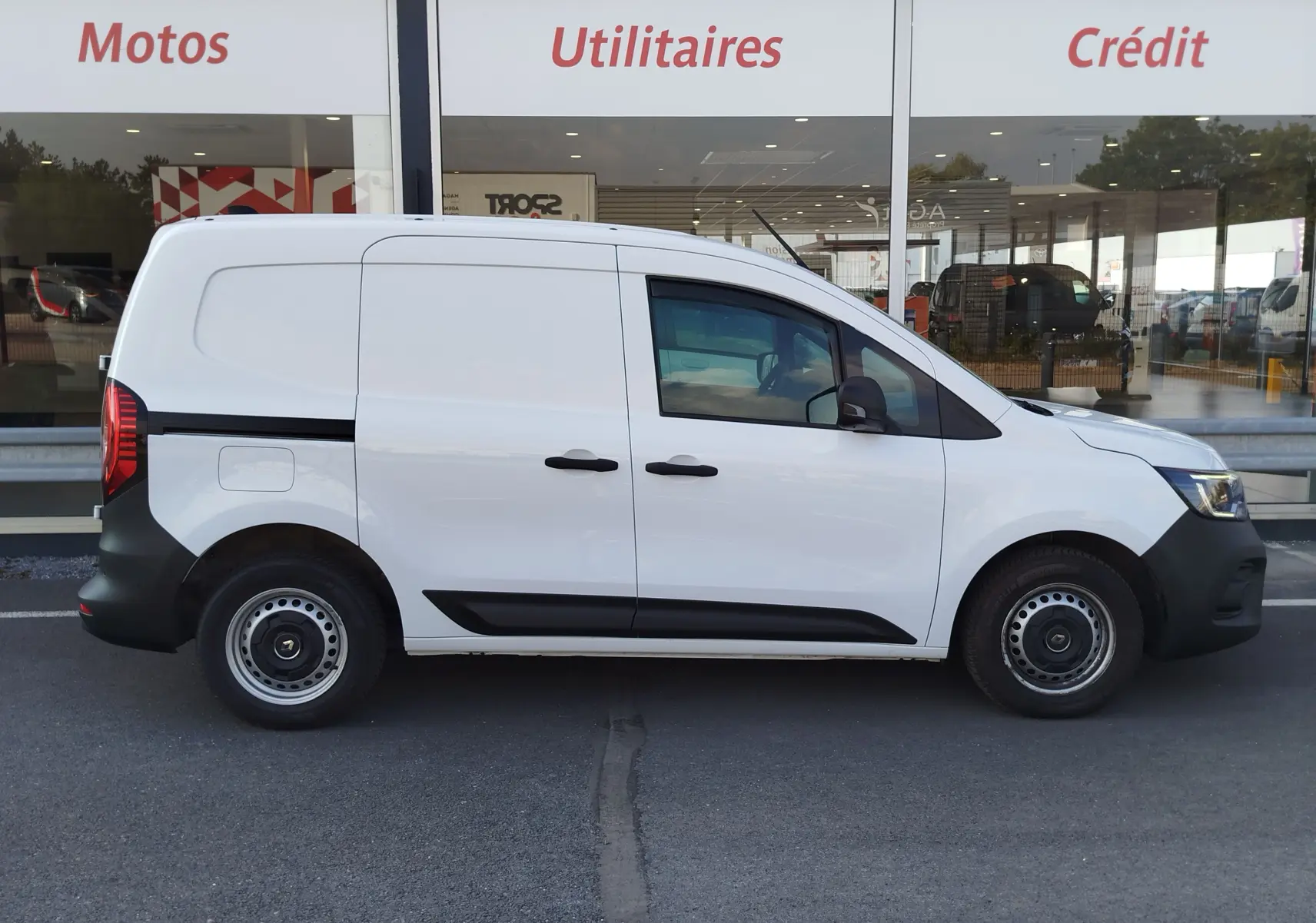 Vue de profil droit d’un Renault Kangoo blanc minéral utilitaire, avec portes latérales coulissantes et jantes acier noires.