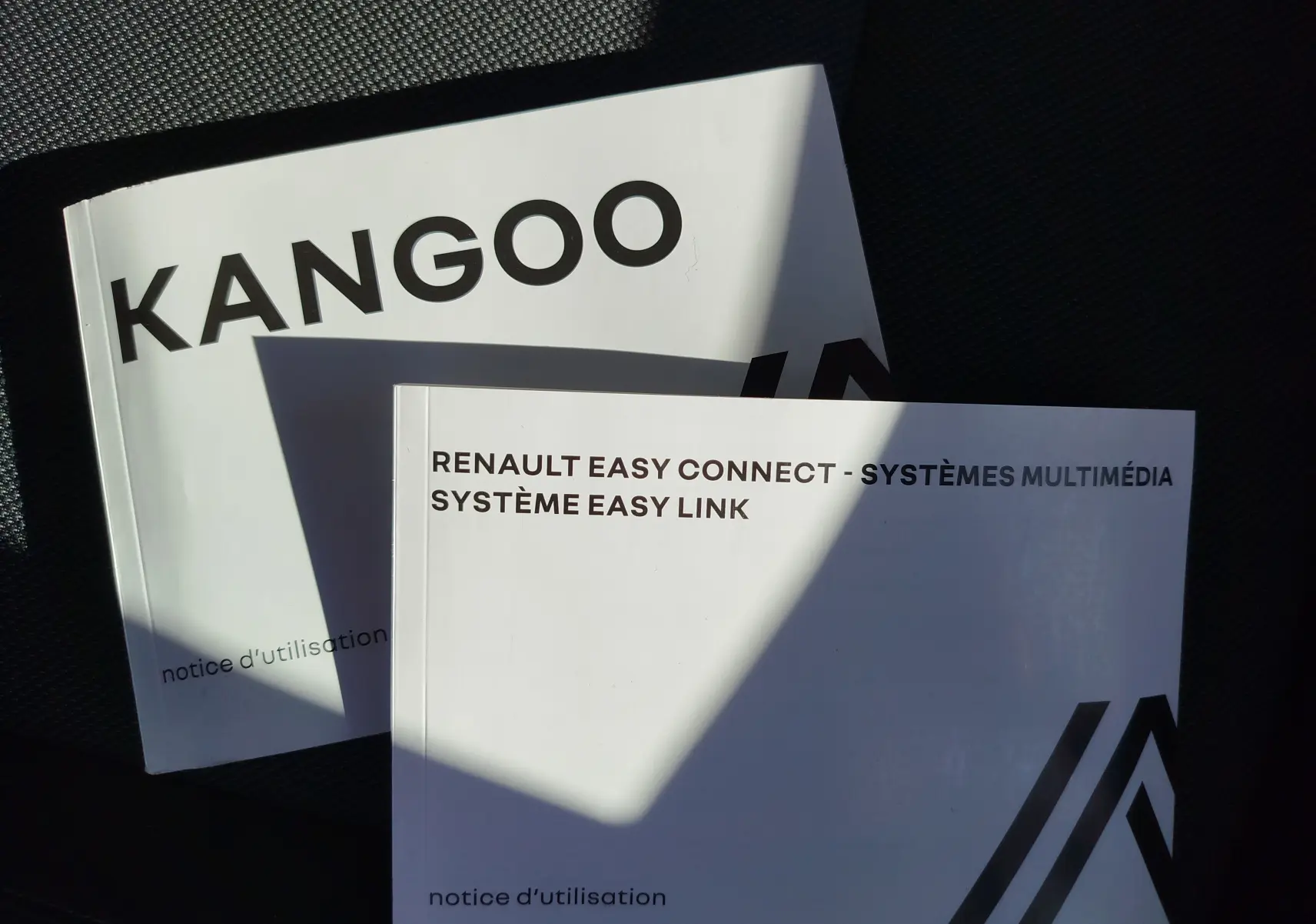 Image montrant deux notices d'utilisation Renault Kangoo posées sur un siège, sans vue du véhicule lui-même.