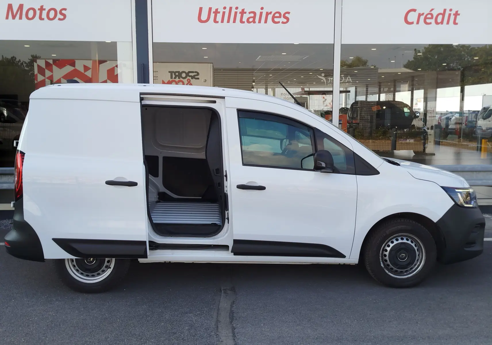 Vue latérale droite d’un Renault Kangoo blanc Minéral 2023 avec porte coulissante ouverte, montrant l’espace de chargement utilitaire.