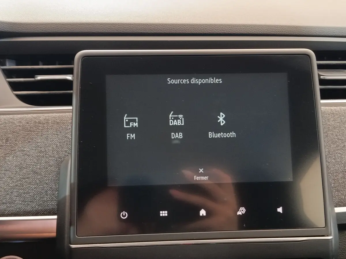 Écran tactile central affichant les sources audio FM, DAB et Bluetooth dans une Renault ZOE Intens blanc, vue intérieure.