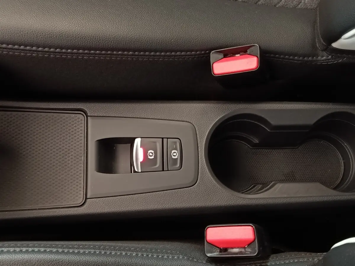 Vue rapprochée de la console centrale noire de la Renault ZOE Intens R110 avec frein à main électrique et porte-gobelets.