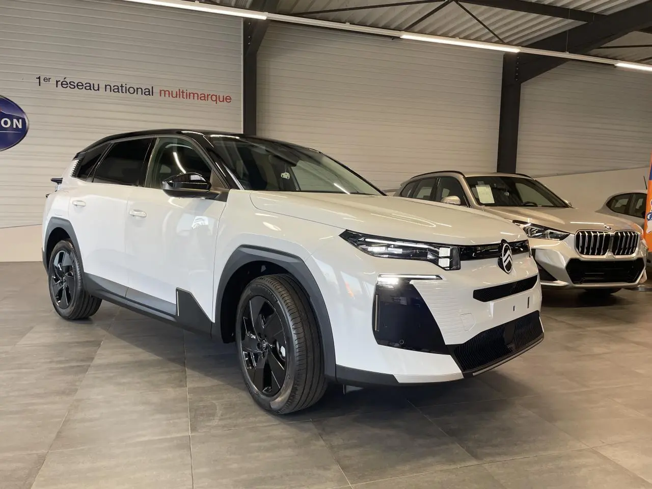 Citroën C5 Aircross blanc Okenite avec toit noir, vue 3/4 avant droit en intérieur showroom.